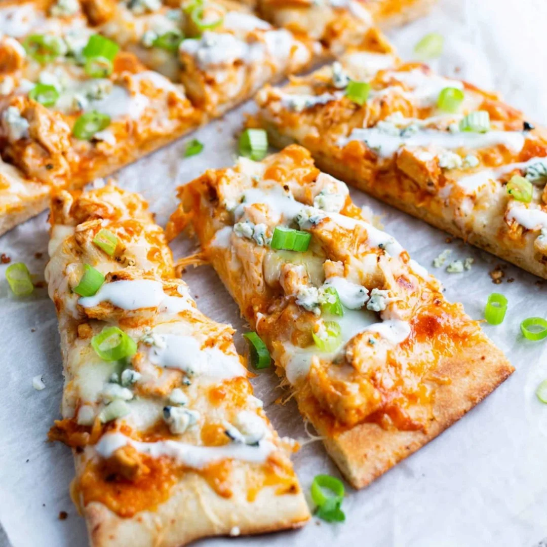 High protein buffalo chicken flatbread topped with cheese and fresh herbs