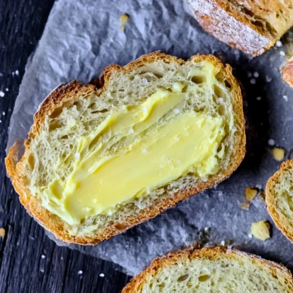 A bright, fizzy blue beverage with granulated salt crystals and a clear jar on a granite surface.