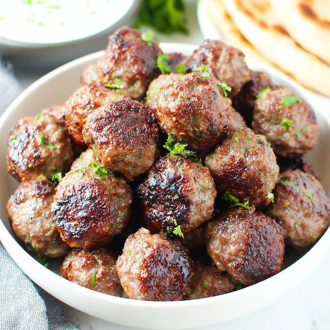 Delicious plate of Greek meatballs (keftedes) garnished with herbs and served with sauce.